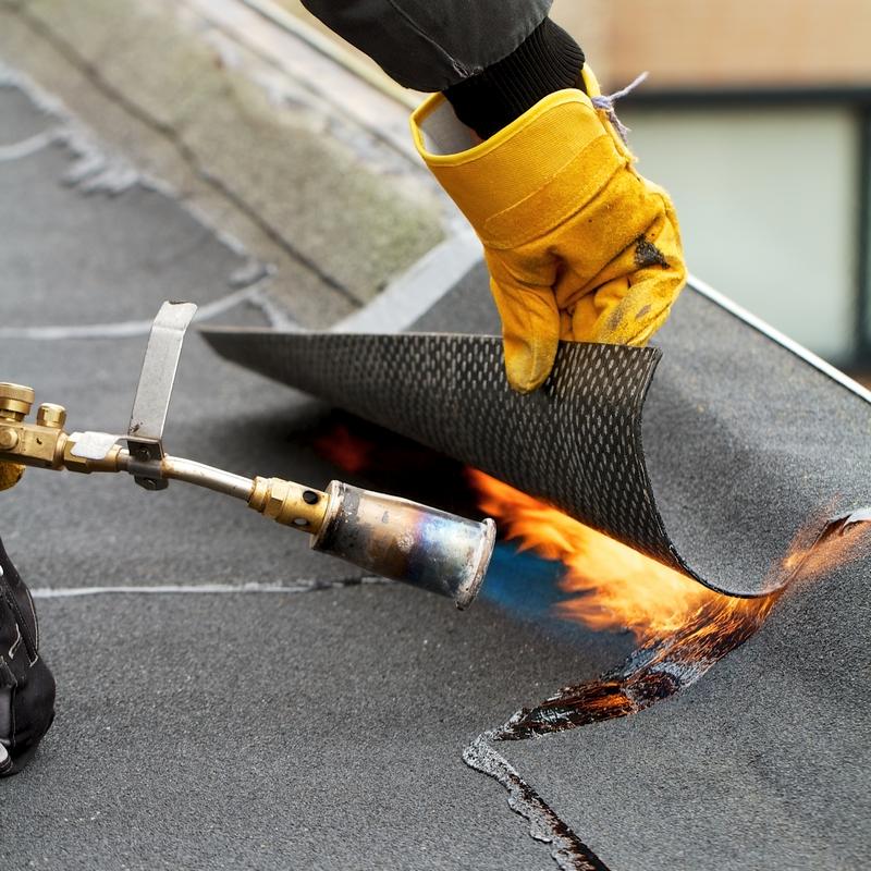 Torch Down roofing being apply on the edge of a commercial roof Impact of roofing materials
